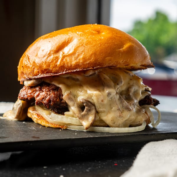 Little Angel Burgers & Wings' burger with a thick patty, melted cheese, mushrooms, and onions.